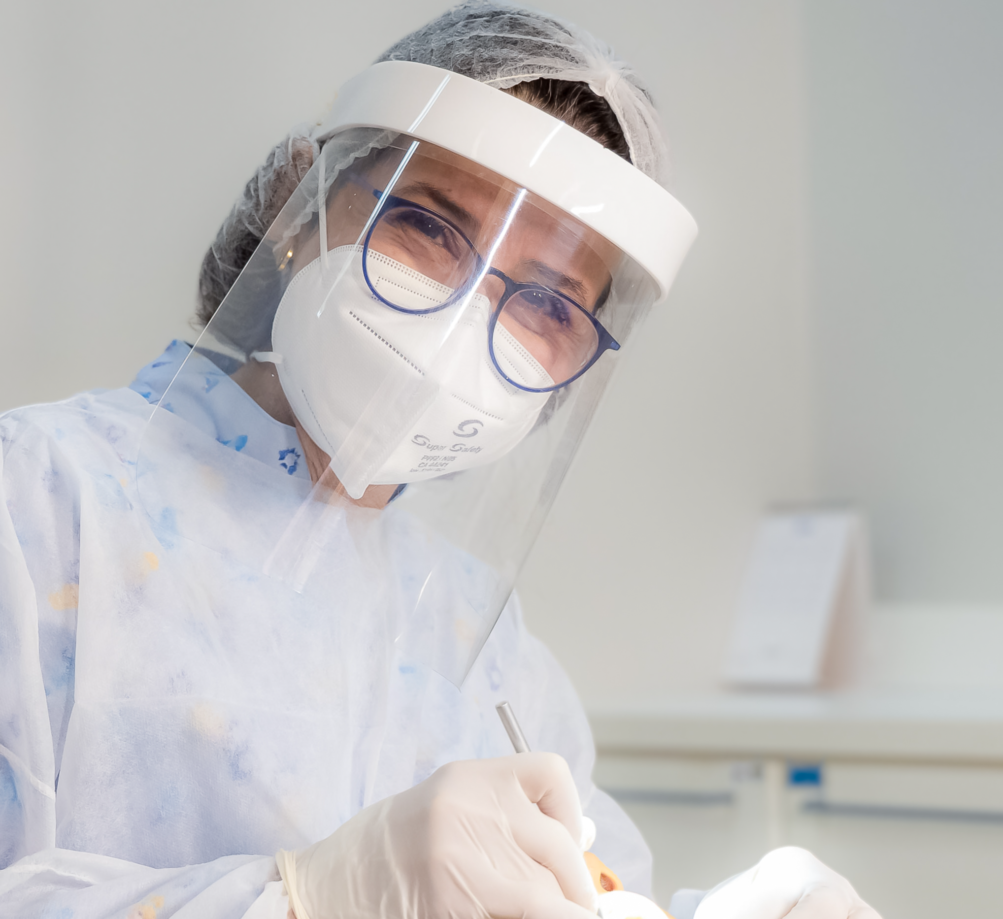 Dentista com equipamentos de proteção manuseando instrumento técnico na boca de paciente